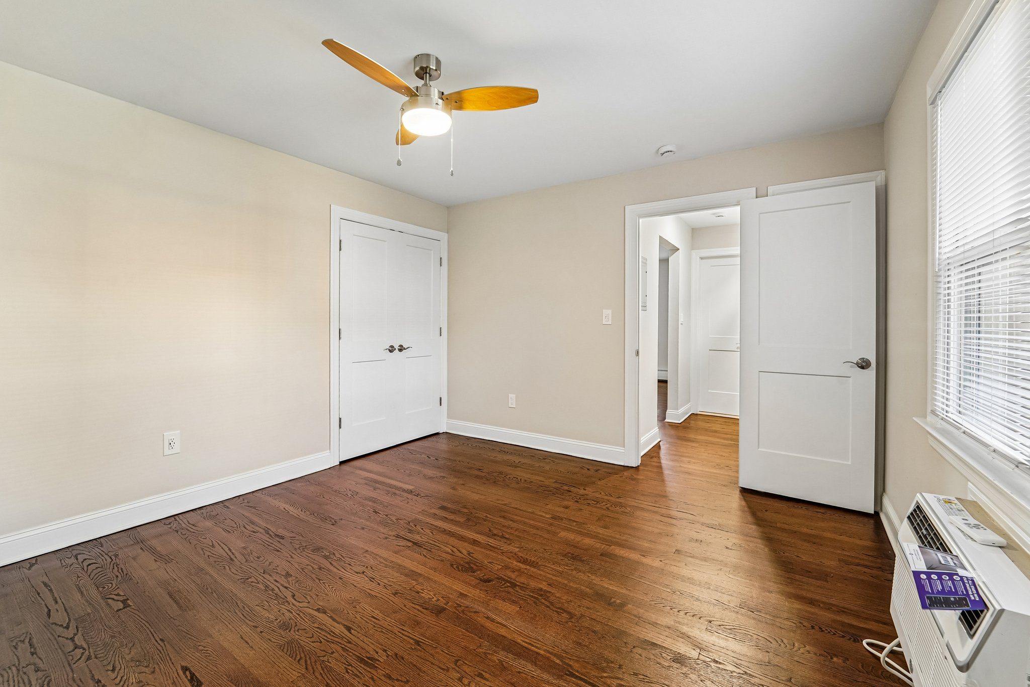 A room with a ceiling fan and wooden floors.